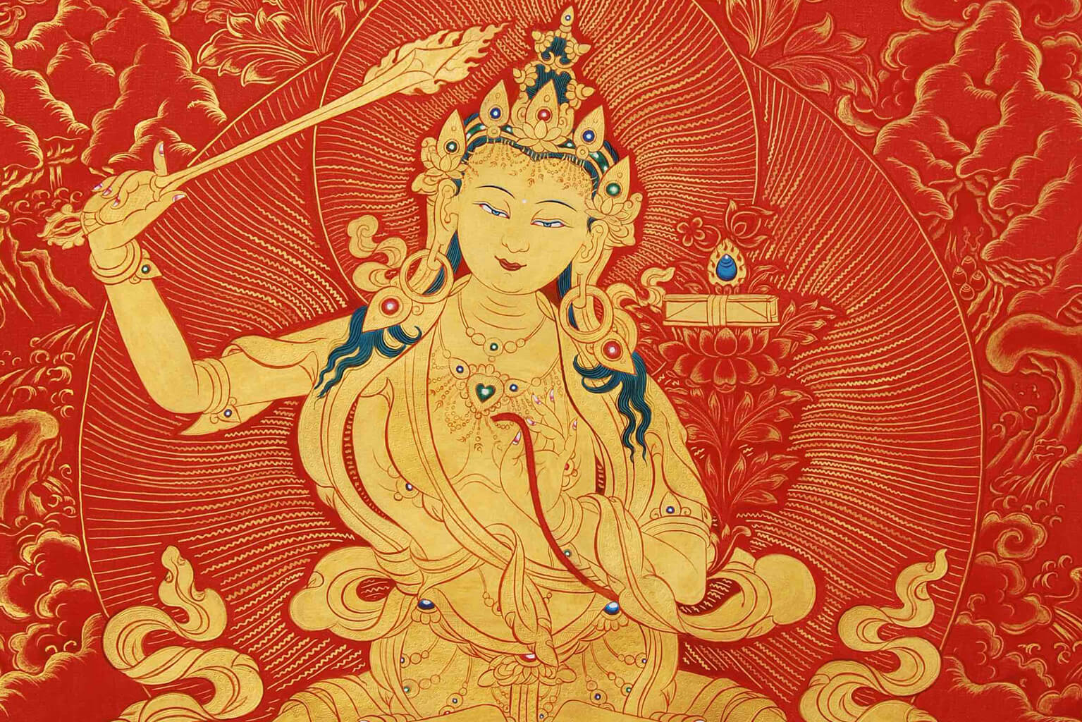 Manjushri is depicted as a male bodhisattva wielding a flaming sword in his right hand, representing the realization of transcendent wisdom which cuts down ignorance and duality. The text supported by the lotus held in his left hand is a Prajñaparamita Sutra, representing his attainment of ultimate realization from the blossoming of wisdom.