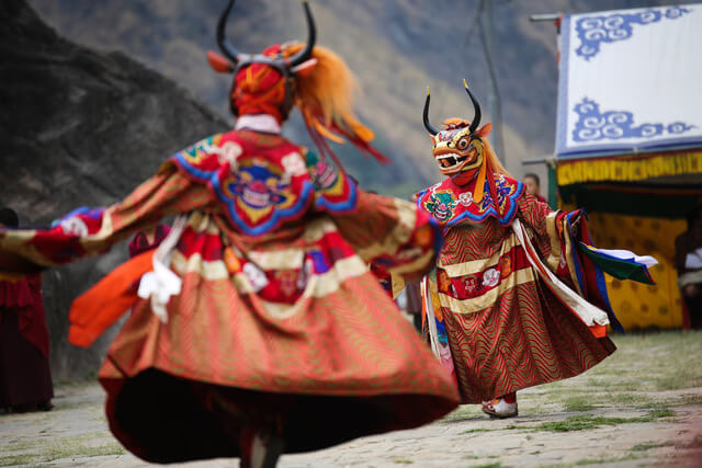 Two monks swirl their robes or red, blue, green and gold as they perform a ritual Cham Dance.