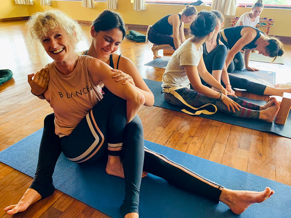 Student on the Elton Yoga Nepal Teacher Training adjusts a fellow student in Seated Twist (Marichyasana C).