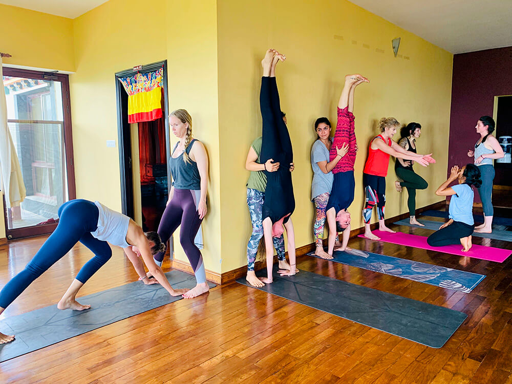 Students on the Elton Yoga Nepal Teacher Training assisting one another in Handstand (Adho Mukha Vrksasana).