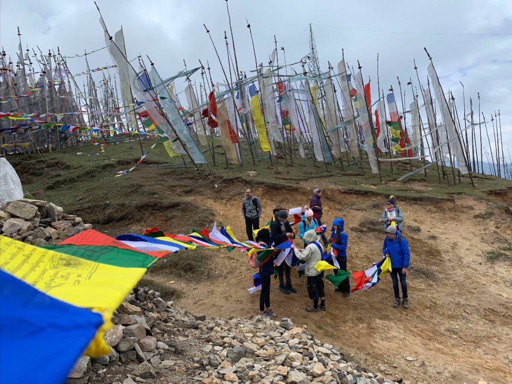 Students on the Bhutan Yoga adventure hanging prayer flags at 4000 m (about 13,000 feet) above Chela La Pass